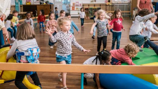 Une petite fille handicapée à l'école maternelle entourée d'autres enfants.